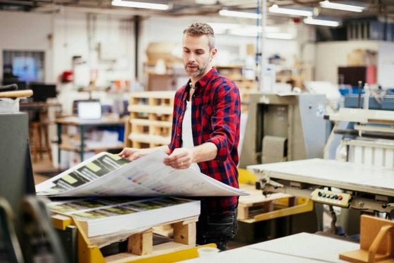 A man looking over a large sheet of printed material